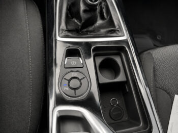 Car center console with gear shift boot, electronic parking brake button, circular drive-mode dial, cup holder, and keys in a tray.