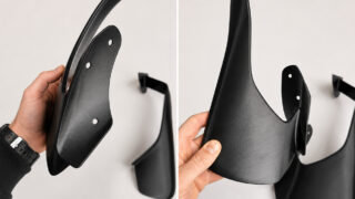Two-panel shot of a black metal wall-mount bracket with a curved hook, held by a hand during assembly.