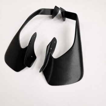 Abstract black sculptural form made of curved leather-like panels on a white background.